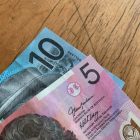 Close-up of Australian 5 and 10 dollar notes on a wooden background.